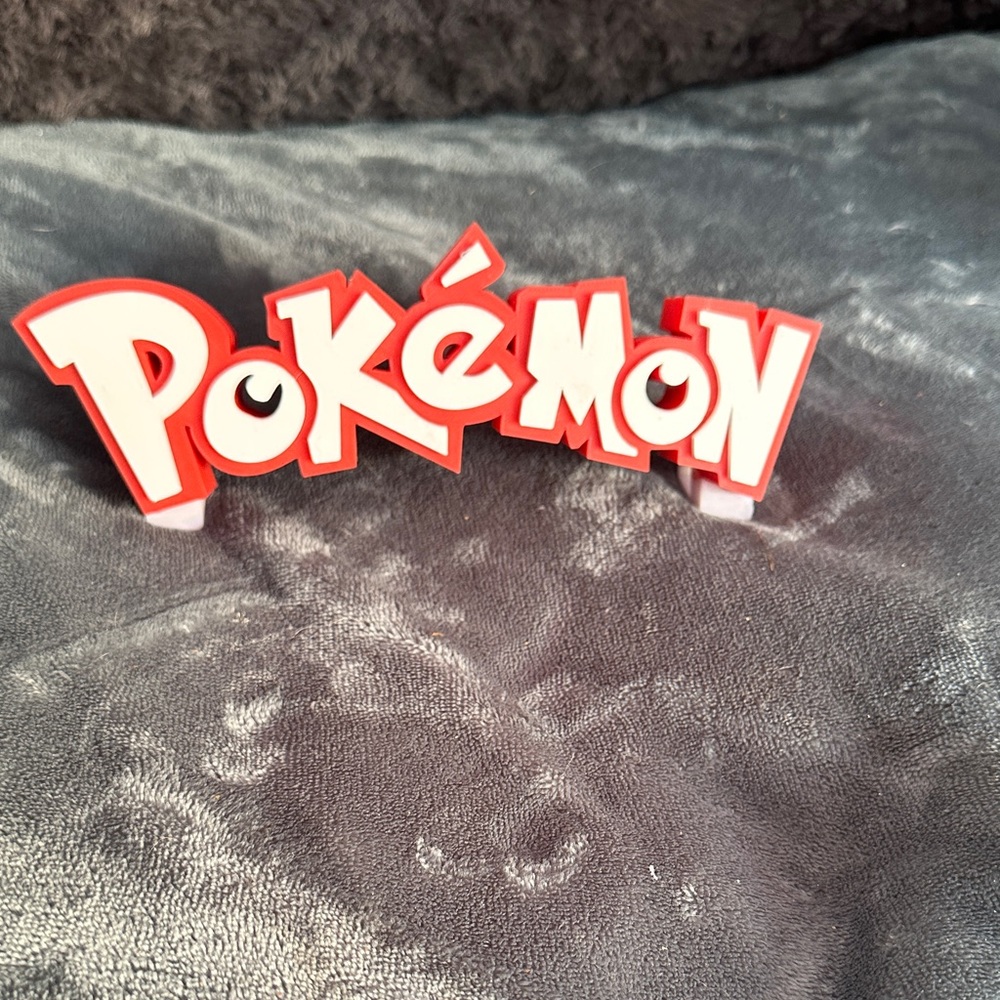 Red and white 3D print Pokémon Logo Display with stand attached